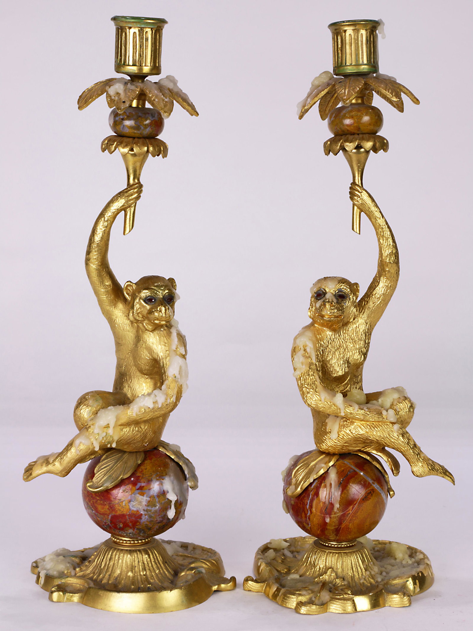 A pair of French ormolu and jeweled candelabra: A pair of French ormolu and jeweled candelabra, each having a single light rising on a figural monkey stem with garnet eyes, and seated on a jasper spherical support terminating on the shaped base, ov