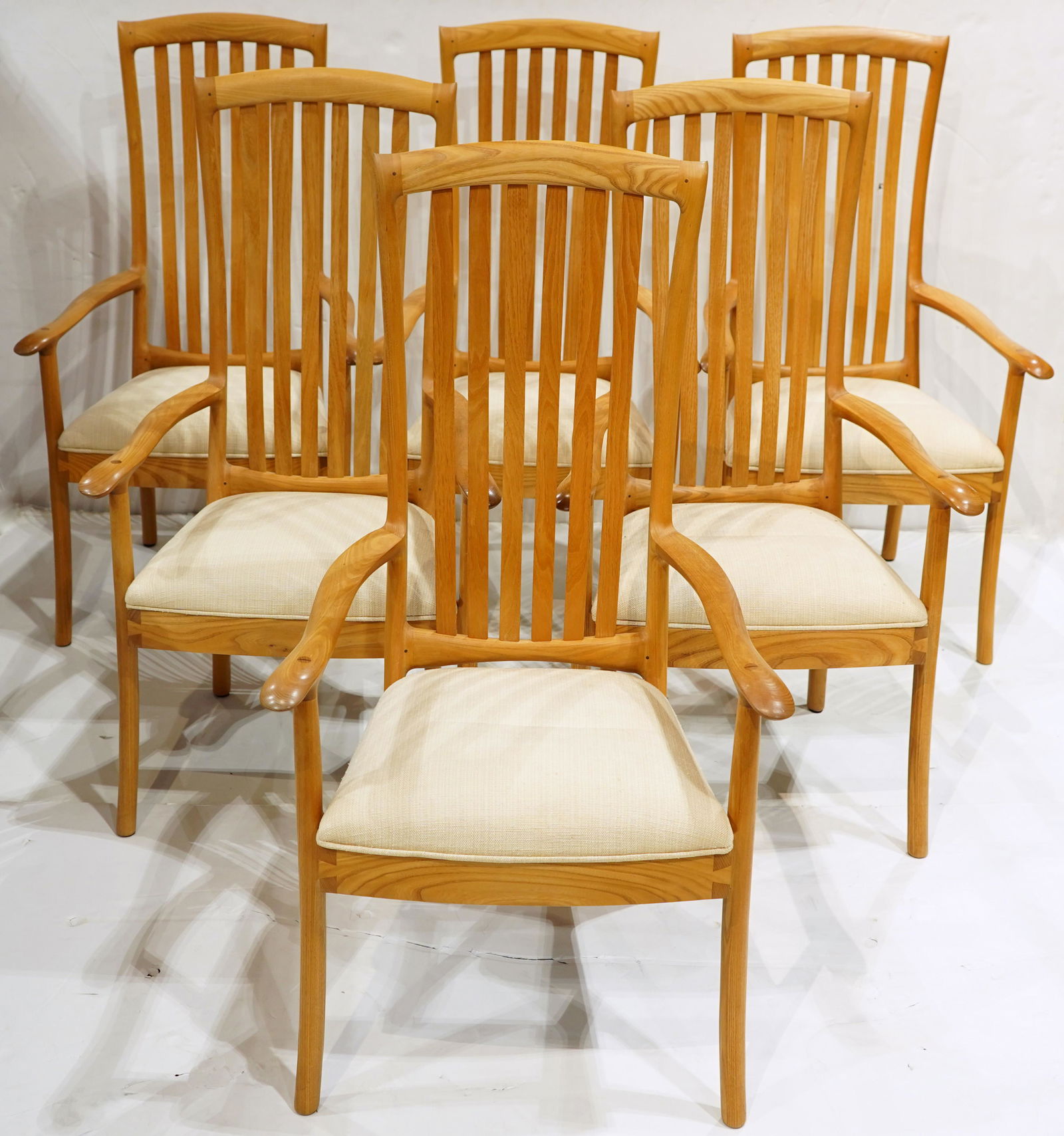 A group of Robert Erickson American studio armchairs: (lot of 6) Robert Erickson American studio armchairs, each having a slatted back, above an upholstered seat, and rising on cylindrical legs, signed and dated on underside, 44"h