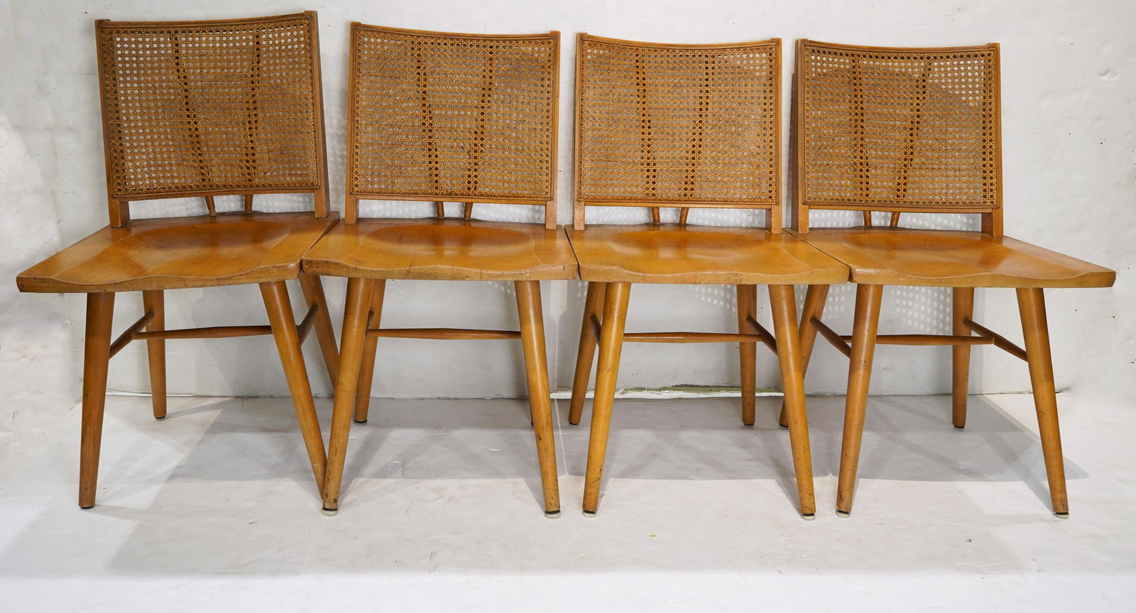 A group of Paul McCobb dining chairs: (lot of 4) Paul McCobb dining chairs, each having a cane back, above a shaped seat and rising on tapered legs, 34"h