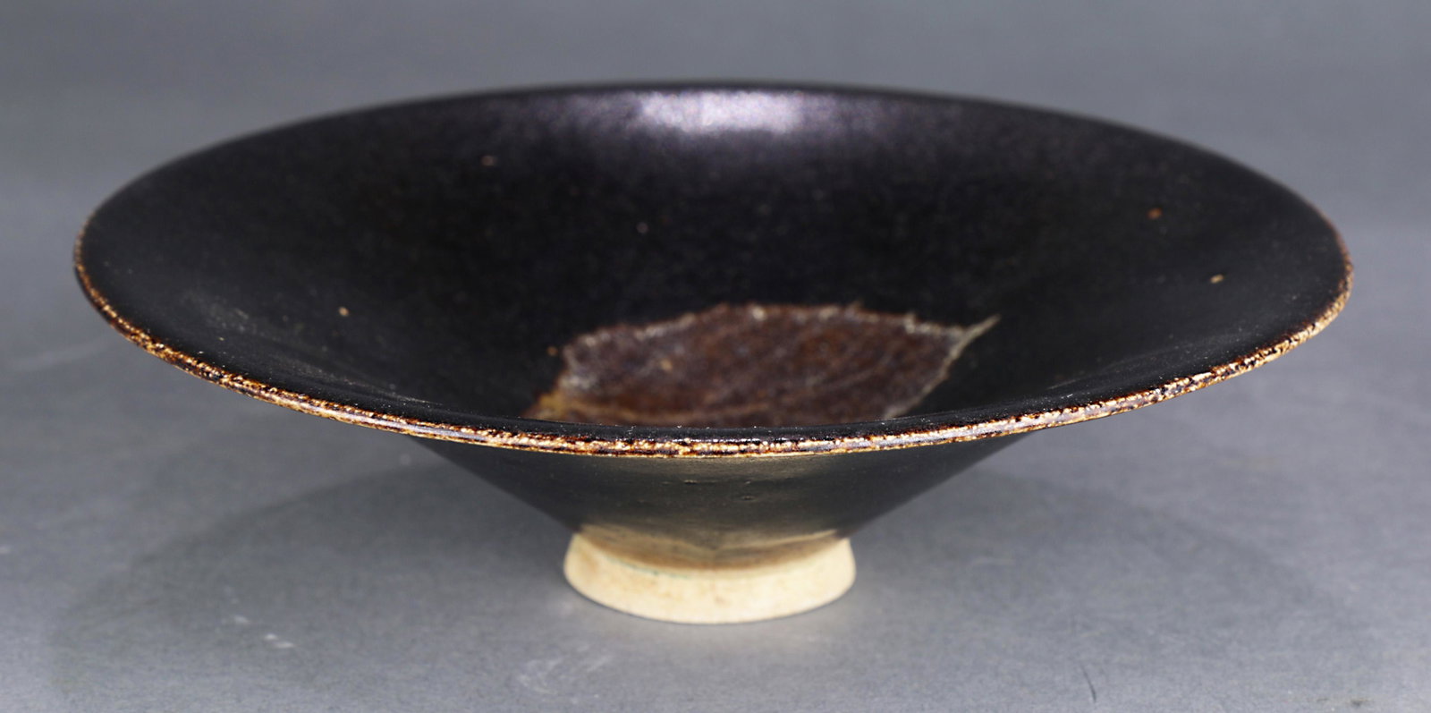 A Chinese Jizhou 'leaf' Tea Bowl: A Chinese Jizhou 'leaf' tea bowl, of conical form with thinly potted wide flaring sides, the interior decorated with the imprint of a leaf burnt in reddish-brown and light buff tones, covered overall 