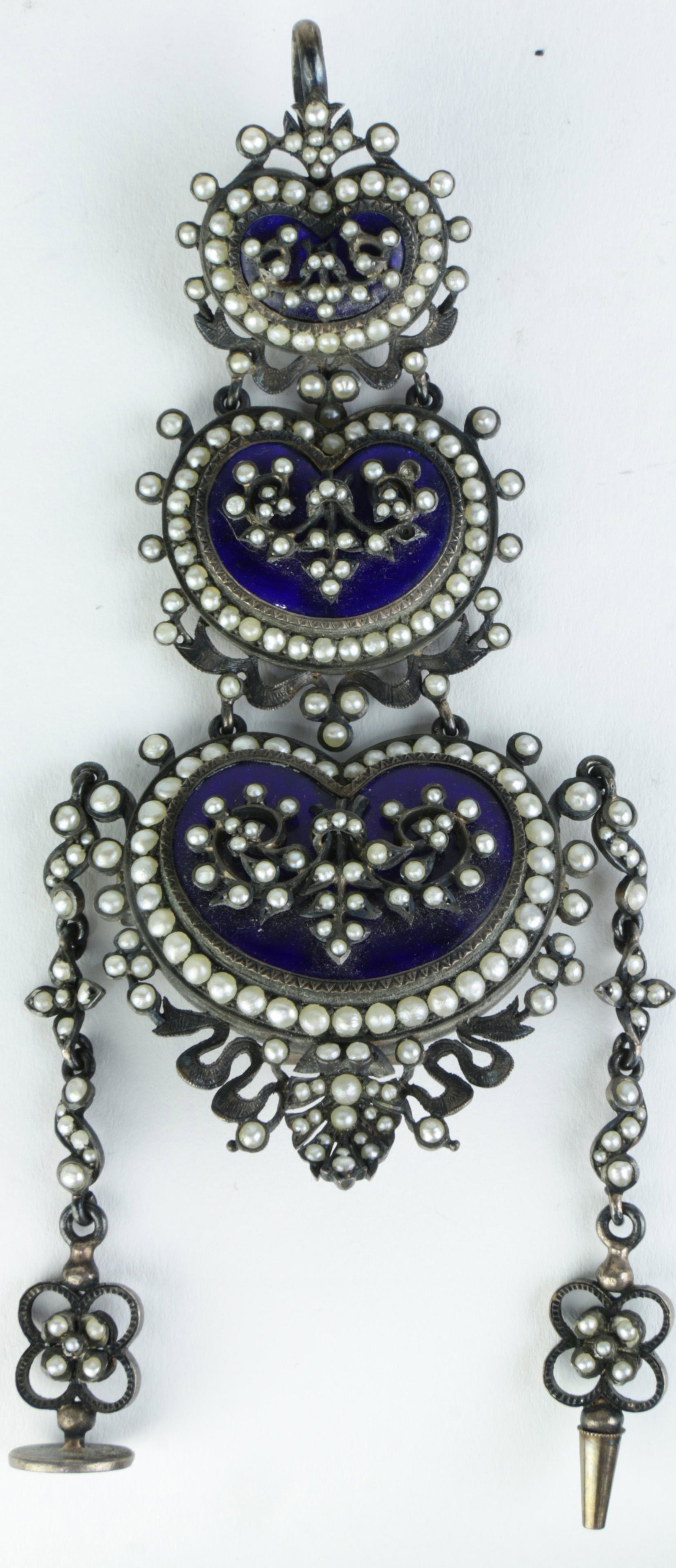 A Continental seed pearl inlaid enameled silver: A Continental seed pearl inlaid enameled silver chatelaine, the pearl inlaid pendant, graduated three tiered cobalt blue enameled heart form holder, fitted with a seal and a conical implement, 4"l