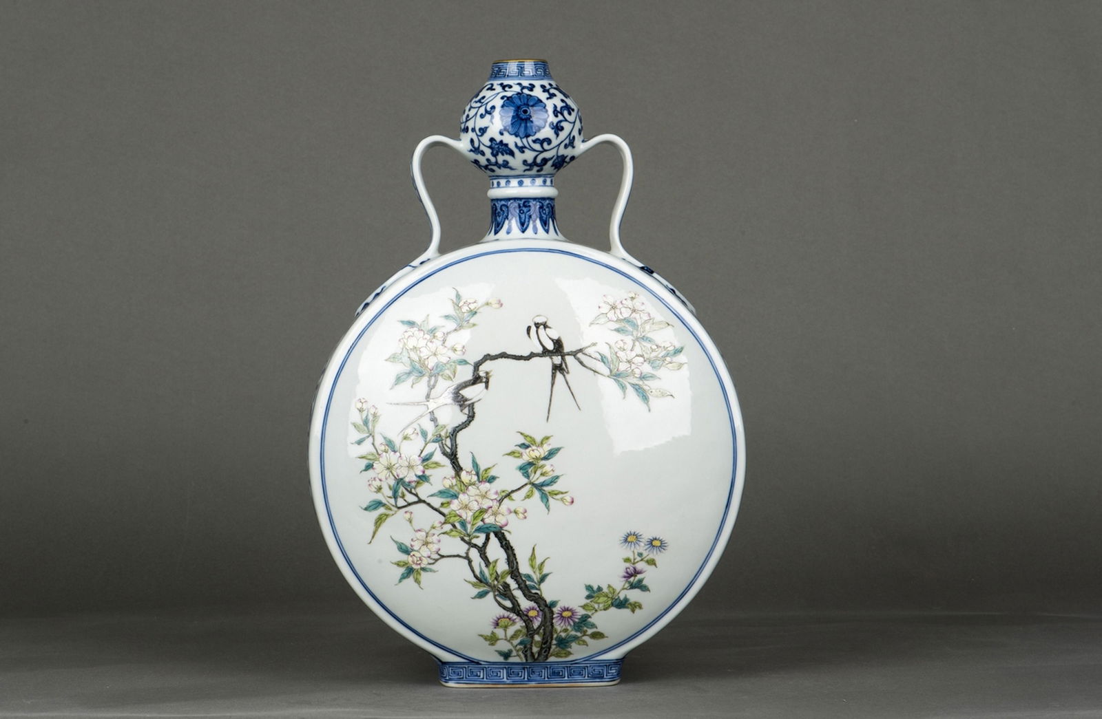 A Chinese underglaze Blue and Famille- rose Enameled: Chinese Famille Rose and underglaze blue moon flask, of flattened globular form rising to a bulb neck, flanked on each side by a pair of handles, rising on a rounded splayed foot with fretwork in unde