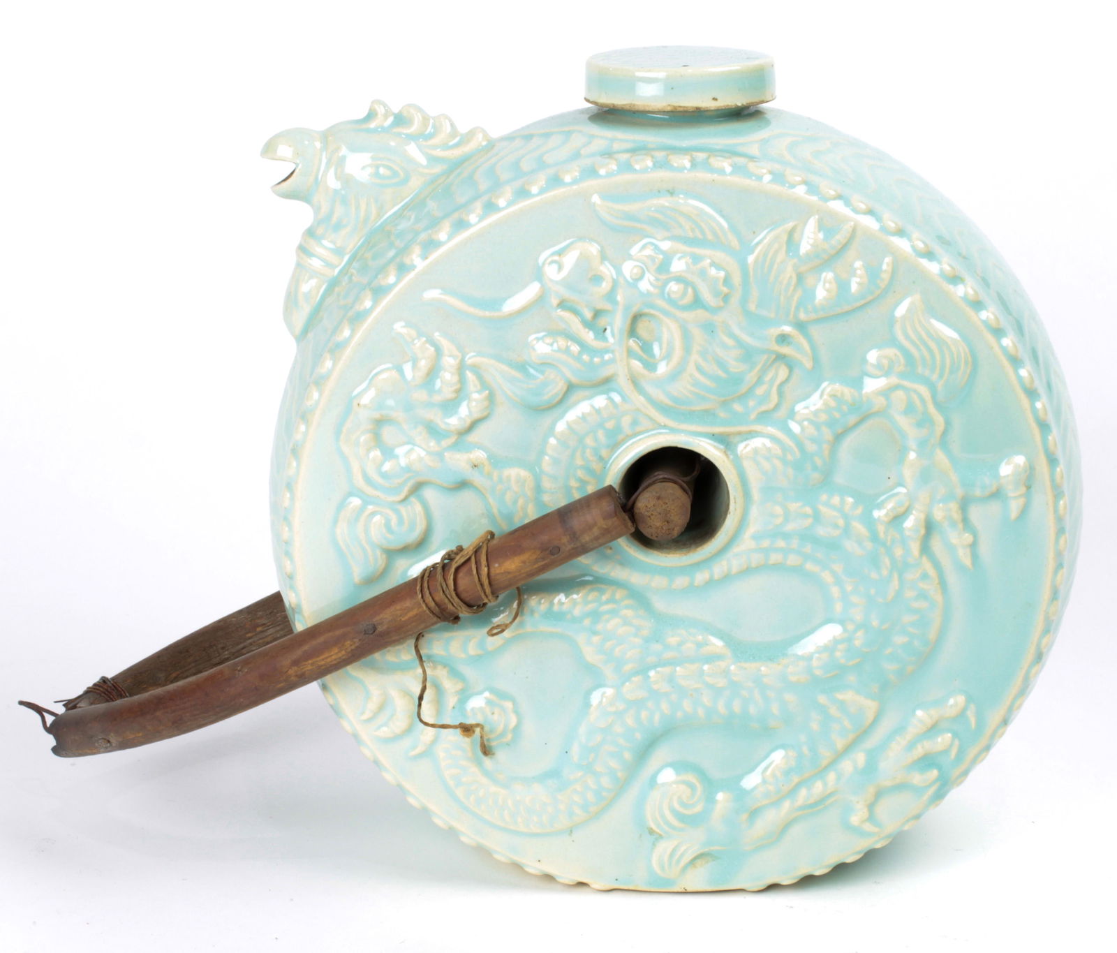 Chinese celadon circular ewer: Chinese celadon circular ewer, the drum shape decorated with dragons in raised relief, a phoenix form spout and an articulated wood handle, 9.5"h x 9"w