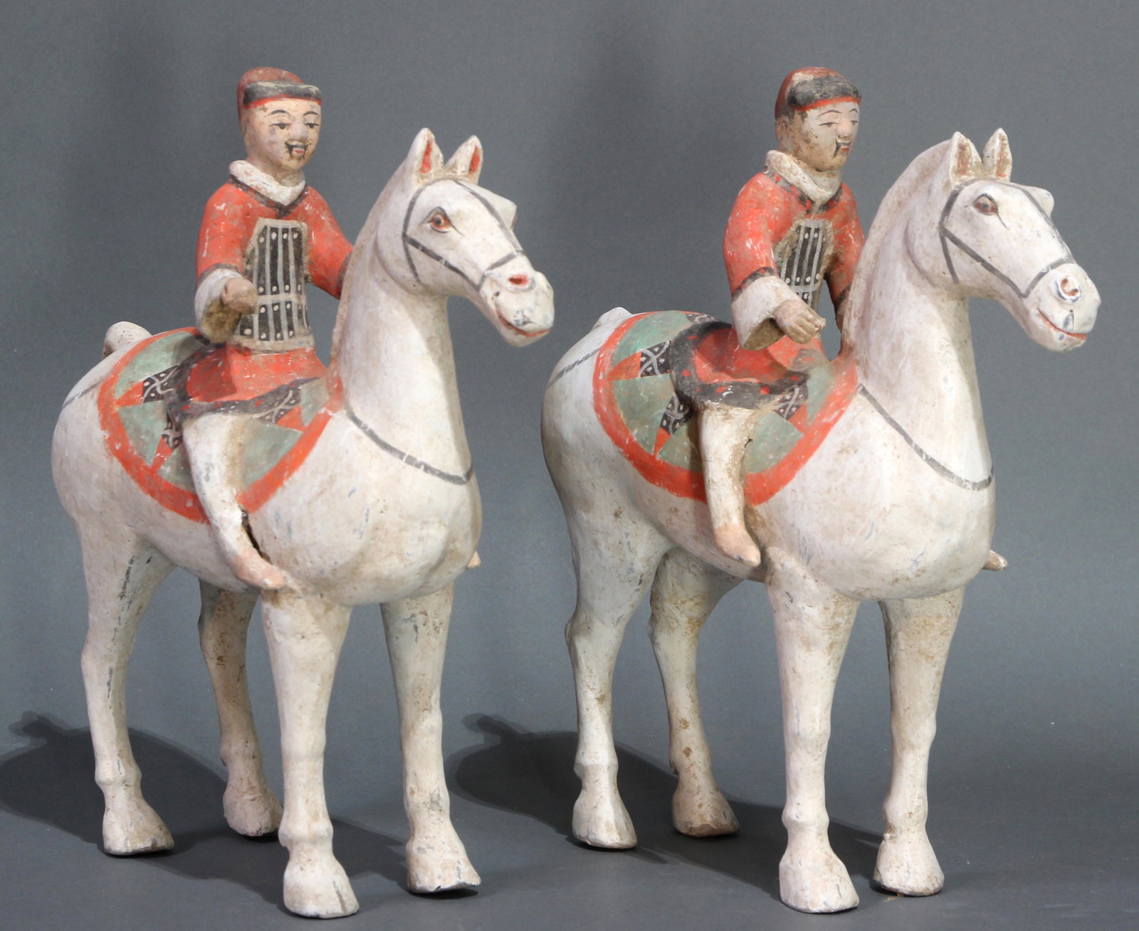 Chinese pair of terracotta figures of horse and rider: Chinese pair of terracotta figures of horse and rider, Han Dynasty (206 AD-220 AD), each white slip decorated horse with an integrated figure of a male groom, modelled with his arms up and hands cuppe