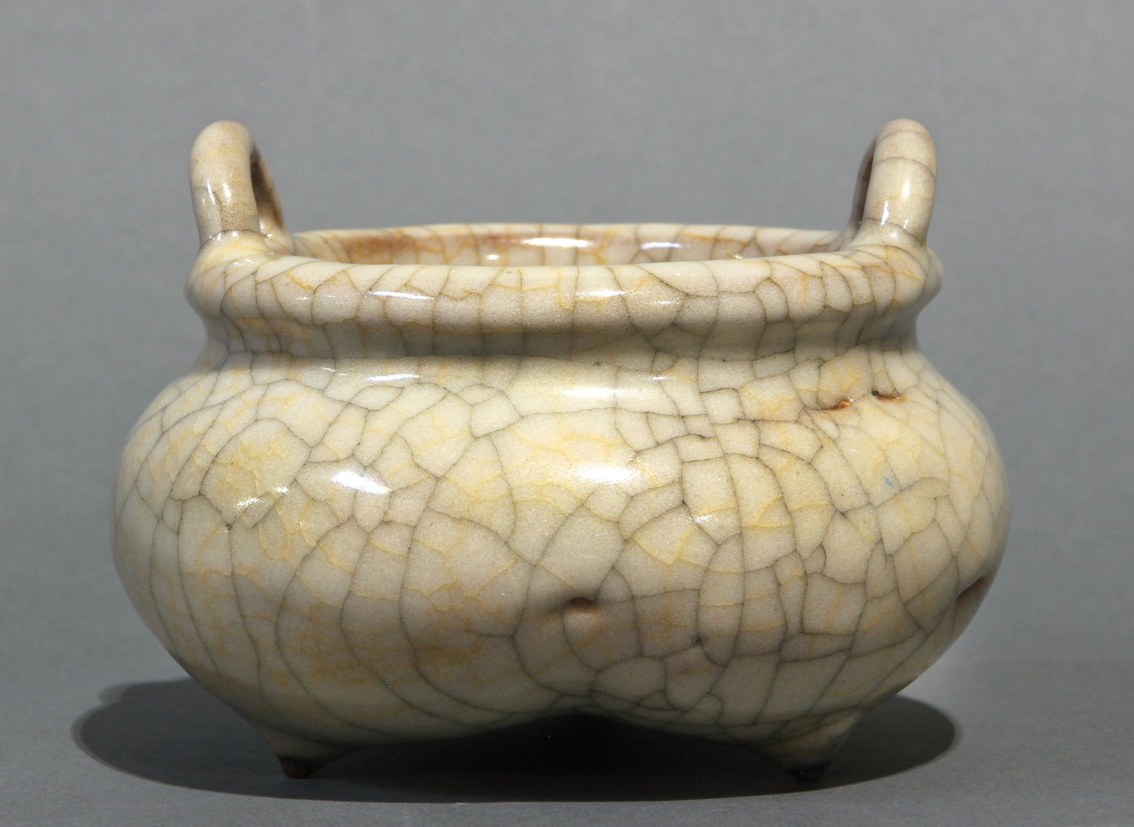 Chinese Ge-type crackle glaze tripod censer: Chinese Ge-type crackle glaze tripod censer, the tripod shallow bowl having a collared rim with twin loop handles, the gray tinged ivory glaze with gold and black crackles, dimensions: 2.5"h x 6"d.