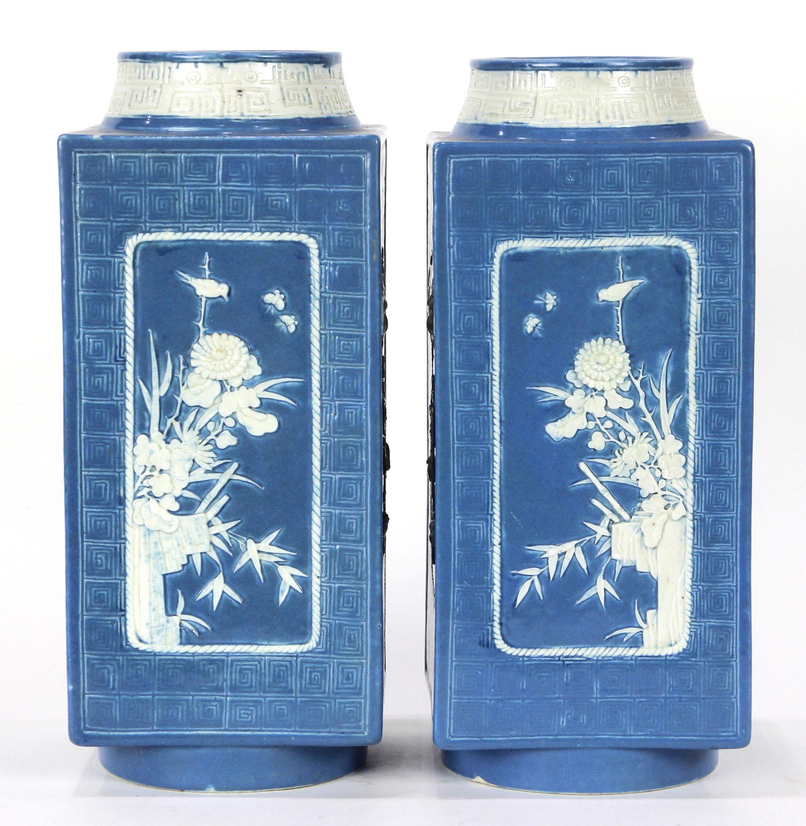 (lot of 2) A pair of blue-grounded cong-form square: (lot of 2) A pair of blue ground white-carving cong vases, each decorated with two rectangular panels depicting chrysanthemum and plum blossom in white and another two side painted with beast-head han