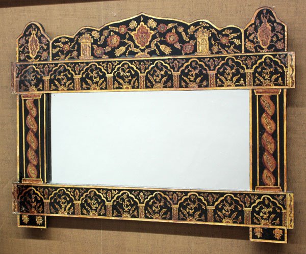 Wall mirror: Wall mirror in a shaped ebonized wood frame with reverse painted glass overlay, enhanced with columns, arches and floral patterns decoration, 21''h x 28''w x .5''d