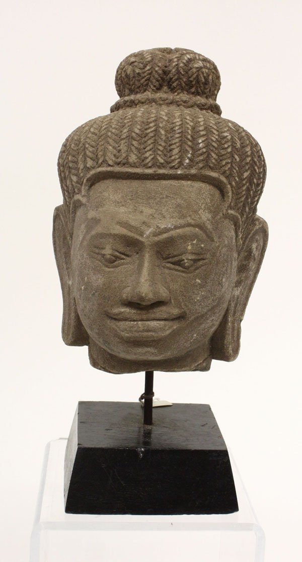 Southeast Asian Stone Head, Khmer: Southeast Asian stone head of a deity, Khmer, Baphuon style, with an elaborate coiffure of plaited tresses pulled up into a high chignon, with a black lacquered stand, 9''h [head only]