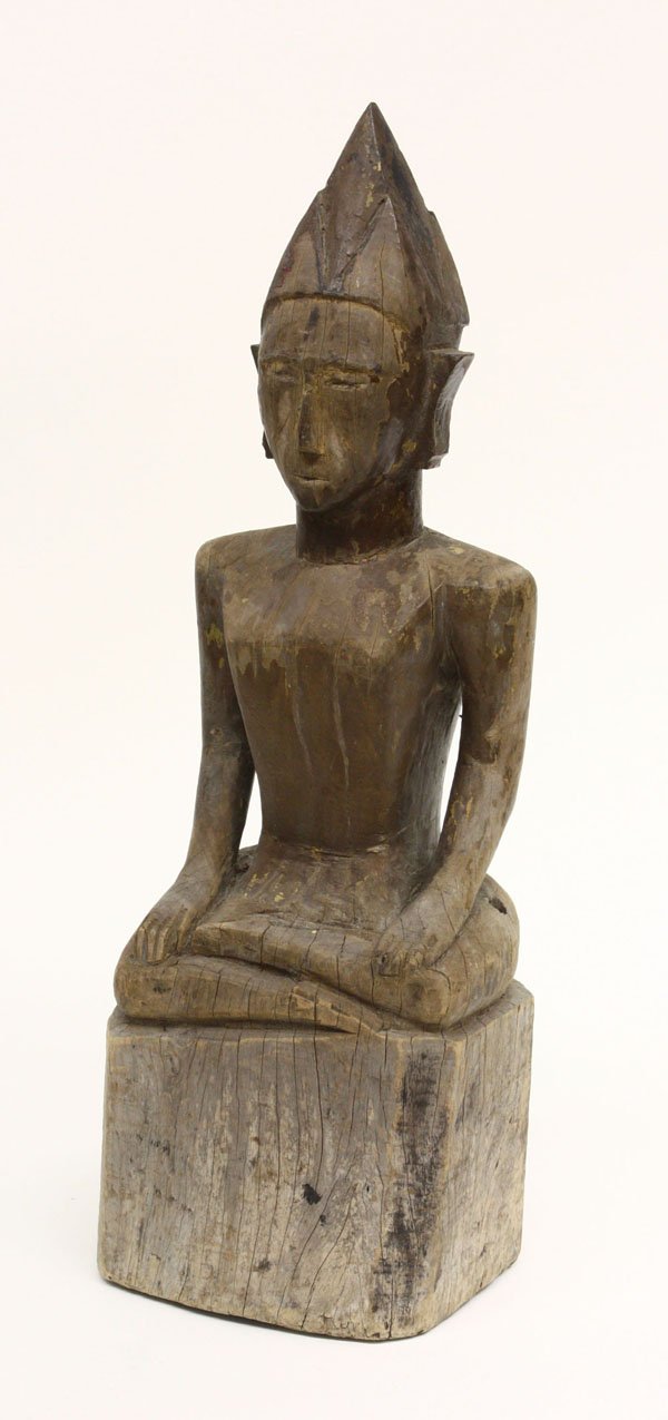 Southeast Asian Wood Deity, Shan State: Southeast Asian wood figure of a deity, probably 19th century, Shan state, seated in a cross-leg pose with both hands resting on his lap, the folk rendering with abbreviated facial features and wearin