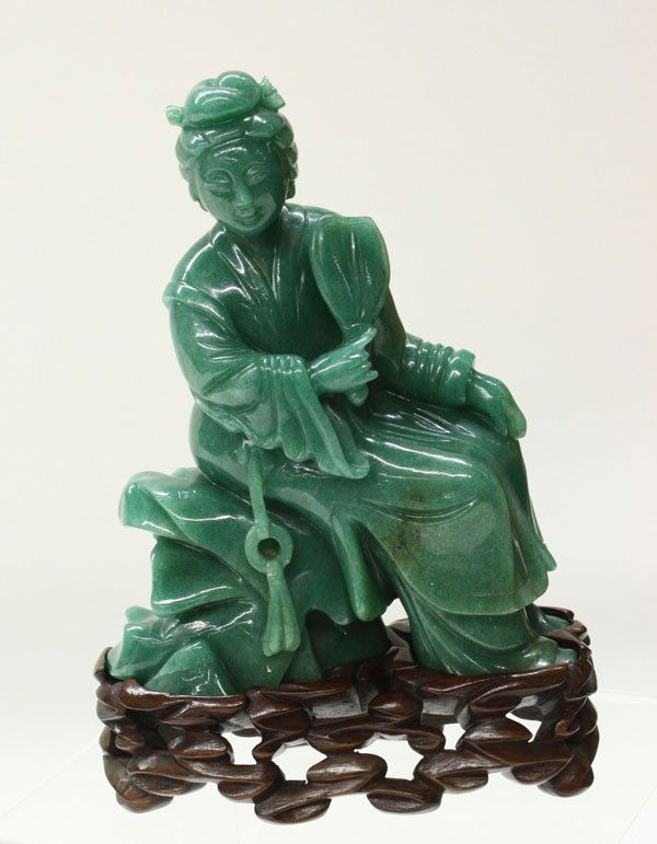 Chinese Green Hardstone Figure, Beauty: Chinese green adventurine stone figure of a meiren, carved and undercut as a maiden seated on a rocky plinth, her right hand with a fan held to one side of her youthful face framed by a elaborate coif