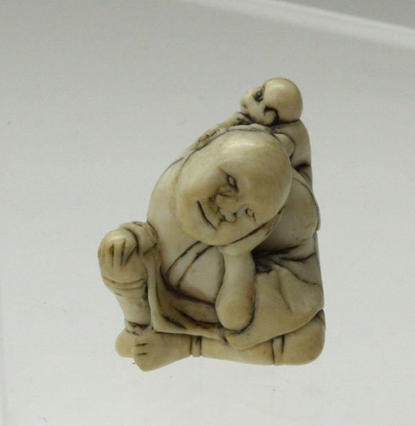Japanese Ivory Netsuke, Monkey Trainer: Japanese ivory figural netsuke, Edo period, 18th/19th century, carved and incised as a monkey trainer seated with one knee raised and resting his head on his left hand, a small monkey clinging to his 
