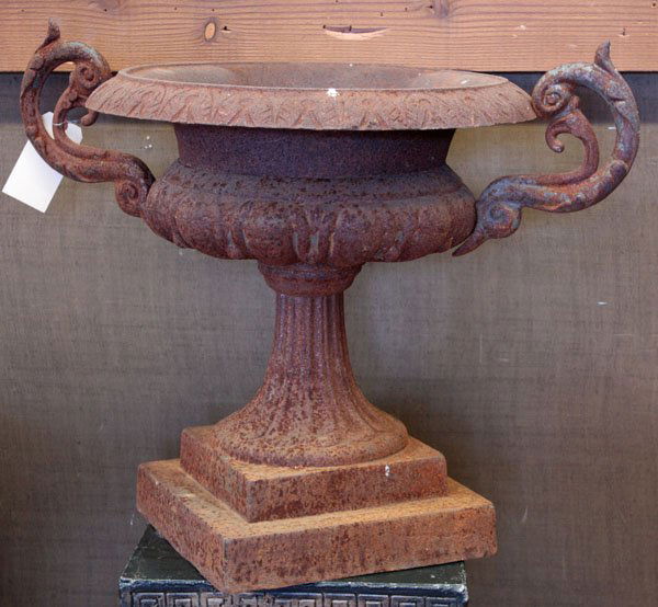 cast iron garden urns: Pair of cast iron garden urns, having low relief patterned lip, double acanthus leaf handles, an exaggerated flaring support, resting on stepped base, 24''h x 31''w