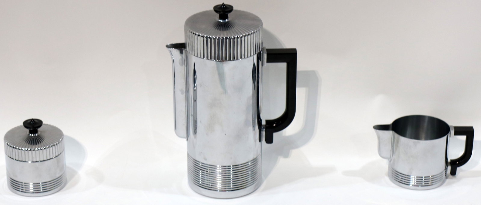 An Art Deco Walter Von Nessen for Chase chrome coffee: An Art Deco Walter Von Nessen for Chase chrome coffee service, no.17054, consisting of a coffee pot, cream and sugar, each with chrome plating, the coffee pot with a black bakelite handle and finial, 