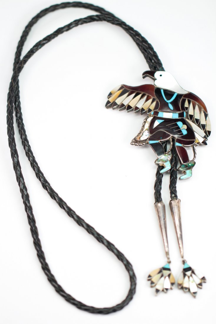 LB Chavez, Zuni multi-stone, silver eagle dancer bolo: LB Chavez, Zuni multi-stone, silver eagle dancer bolo tieDesigned as an eagle dancer, featuring inlaid agate, shell, abalone, turquoise, silver bolo, measuring approximately 88 X 74 mm (marked LB Chav