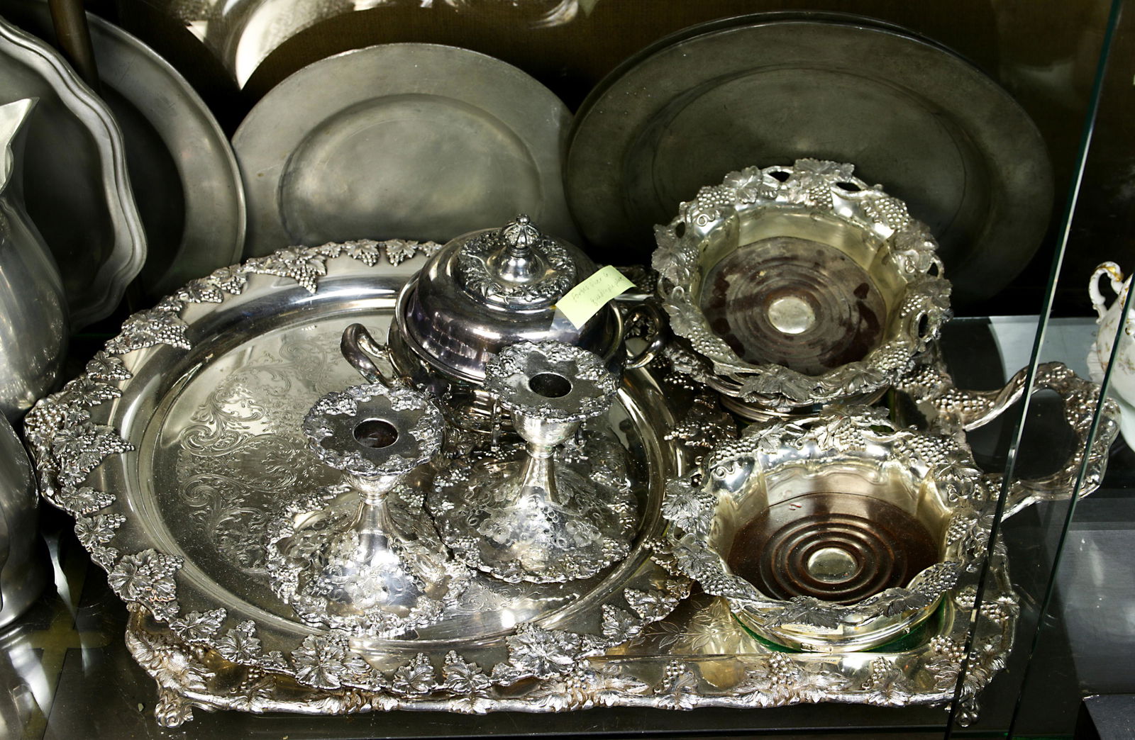 (lot of 8) Silver and quadruple plate hollow ware table: (lot of 8) Silver and quadruple plate hollow ware table articles: each piece decorated with bunch of grapes, including a tea tray 1"h x 24"l x 15"d, a pair candlestands, (3) wine coasters and a Forbes
