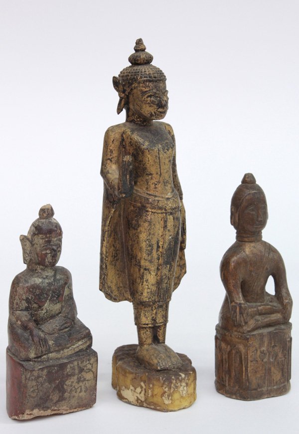 Southeast Asian Wood Buddha Figurines: (lot of 3) Southeast Asian wood figures of the Buddha, probably Thai, the first standing with the right hand in the abhaya mudra ('fear not' gesture), the second seated on a high plinth and in the bhu