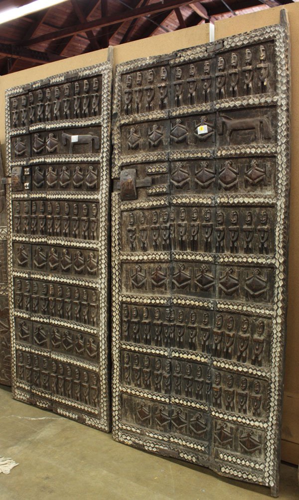 Wood carved doors, Dogon style, Mali: (lot of 2) Wood carved grainery doors, Dogon style, Mali, multi-figural carvings, slide latches, the largest 78''h x 34''w