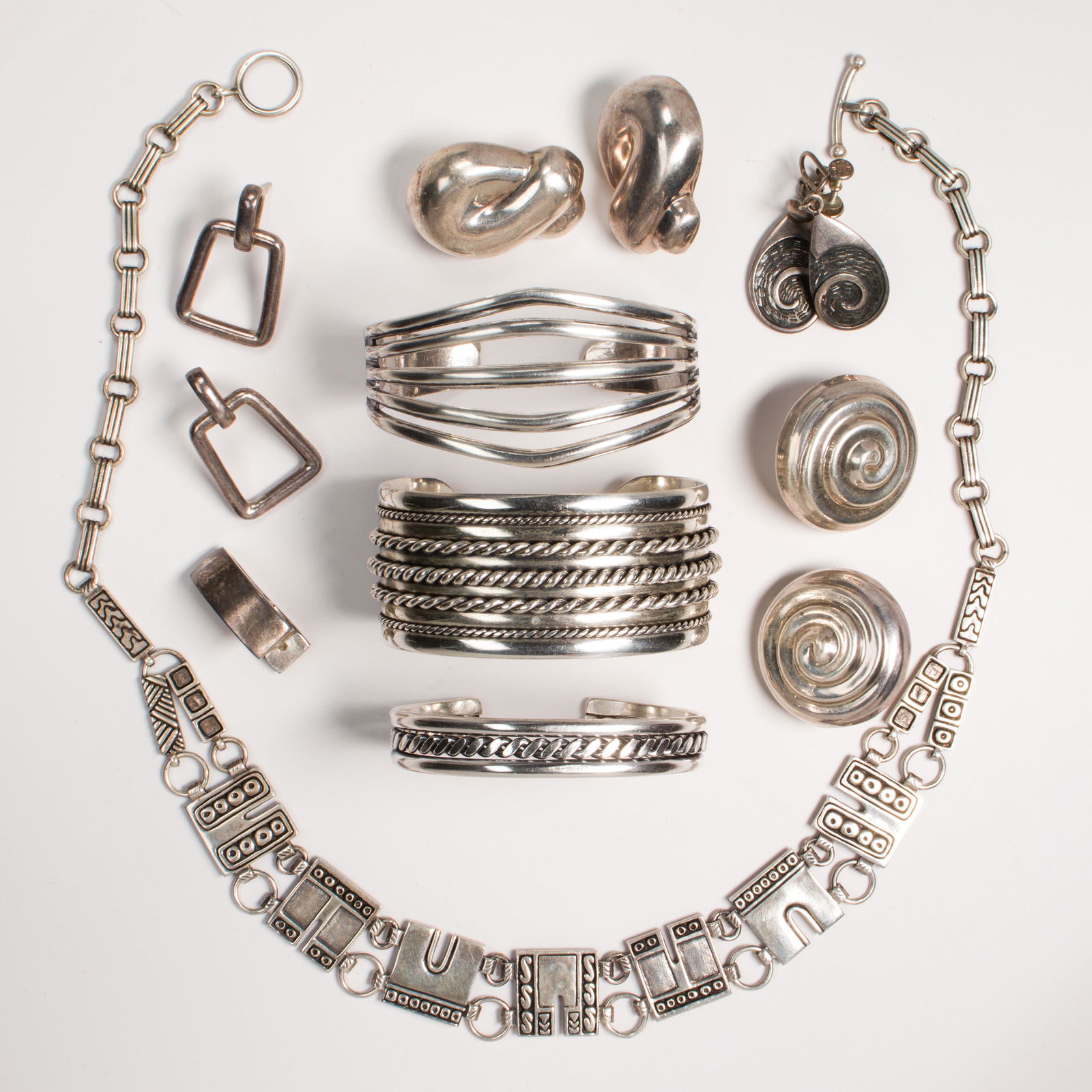 A group of silver jewelry: A group of silver jewelryincluding a necklace; Three cuff bracelets; Four pairs of earrings; A single unmatched earring. Gross weight: 214.9 gs.