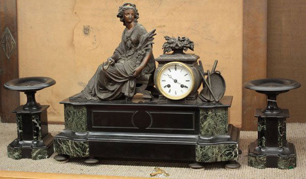 Marble spelter mantle clock: (lot of 3) Marble, bronze and patinated spelter figural mantle clock and garniture set, depicting seated Demeter, sickle in hand with fruits of the harvest, atop large black and variegated black and g