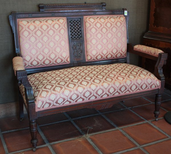 Eastlake settee in the Aesthetic taste: Eastlake settee in the Aesthetic taste, having carved barley twist and low relief pattern crest rail, pierced latticework back panel, rose coloured floral damask upholstery, 40''h x 53''w x 21''d