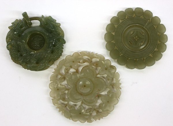 Chinese Green Jade Disks: (lot of 3) Chinese green jade decorations,a pendant with confronted dragon framing a moveable shou medallion, and two reticulated disks, one with a central blossom, the other with a moveable center, l