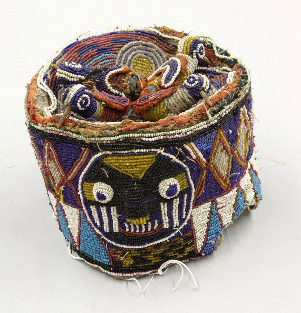 Beaded ceremonial cap Yoruba Nigeria: (Lot of 2) Beaded ceremonial caps, Yoruba tribe, Nigeria, one embellished with mask and floral decoration against a white ground, with red beaded band around cap's edge, 4''h x 7''d, the other with va