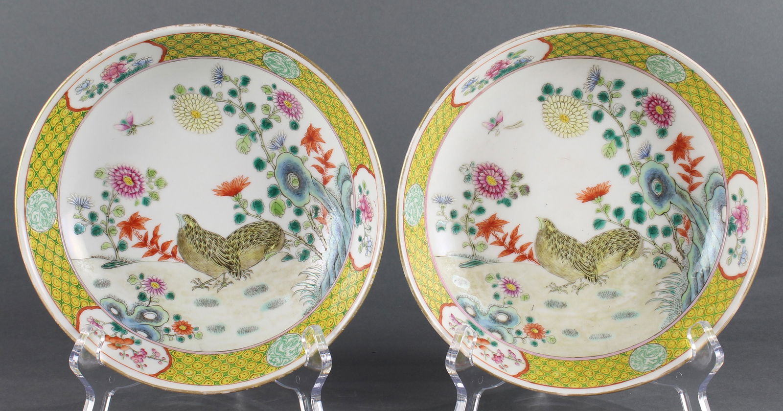 A pair of Chinese Famille rose plates: A pair of Chinese Famille rose plates, each shallow bowl enamel painted with twin partridges in a garden landscape with chrysathemums, a yellow diaper pattern with dragon and floral reserves, each Gua