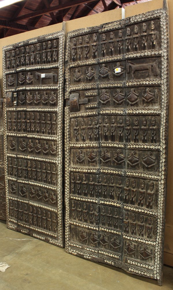 Wood carved doors, Dogon style, Mali: (lot of 2) Wood carved grainery doors, Dogon style, Mali, multi-figural carvings, slide latches, the largest 78''h x 34''w