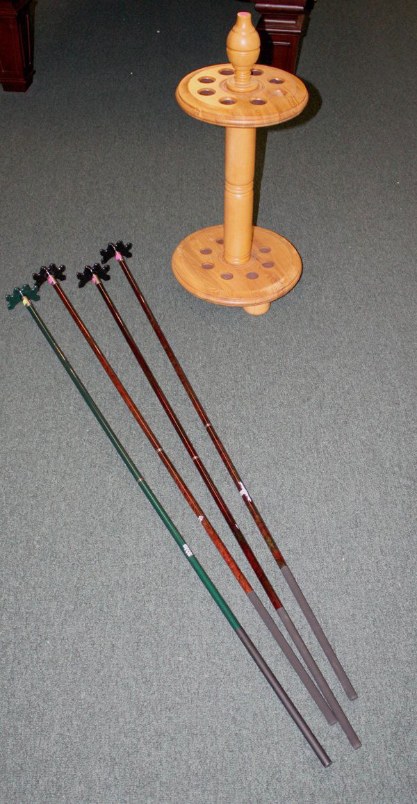 pool cue rack and four bridge sticks: (lot of 5) pool cue rack on three bun feet with slots for eight cues together with four bridge sticks, three in mahogany and one in green finishes All items must be paid for and picked up by 3 p.m. T