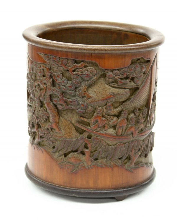 Chinese Bamboo Brush Pot: Chinese stained bamboo brush pot, the exterior carved and undercut with a continuous scene of figures in a landscape with a river navigated by a boat and bordered by bamboo groves and rustic dwellings