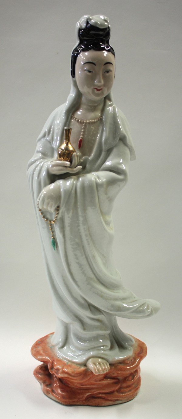 Chinese Porcelain Guanyin: Chinese porcelain Guanyin figure, standing in flowing white robes with a gilt amphora in one hand and a chain of prayer beads in another, the benevolent face framed by a white cowl, the unglazed base