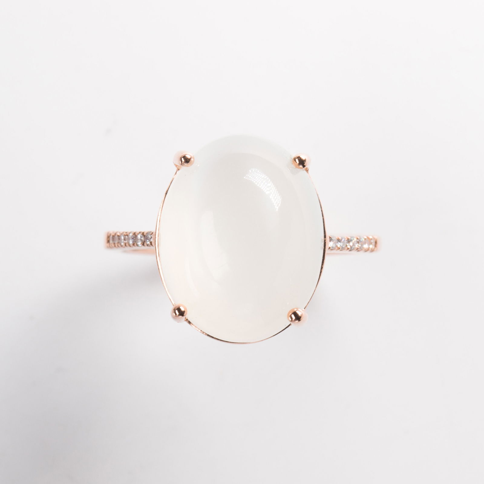 A moonstone and fourteen karat rose gold ring: A moonstone and fourteen karat rose gold ringdesigned as an oval cabochon moonstone, measuring approximately 15.0 x 11.8 x 6.6 mm, flanked by round brilliant-cut diamond shoulders. 2.7 dwt; Size: 7