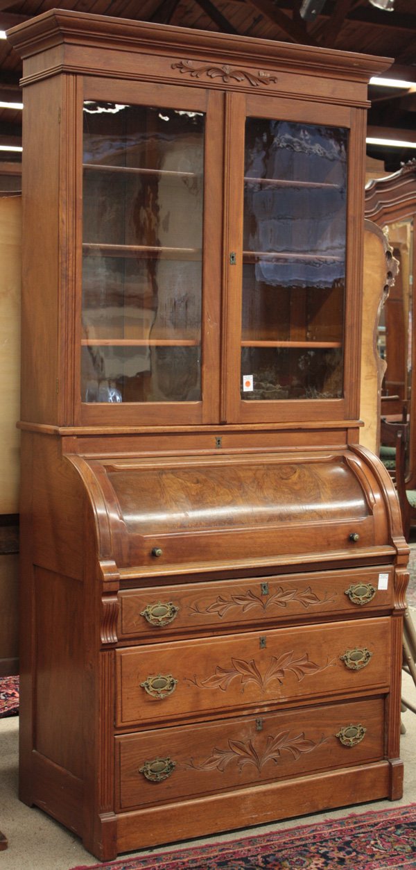 Victorian walnut secretary bookcase: Victorian walnut secretary bookcase with cornice molded top centered with floral relief over double glass doors, the lower section cylinder roll revealing pull-out writing surface inset with baize, ov