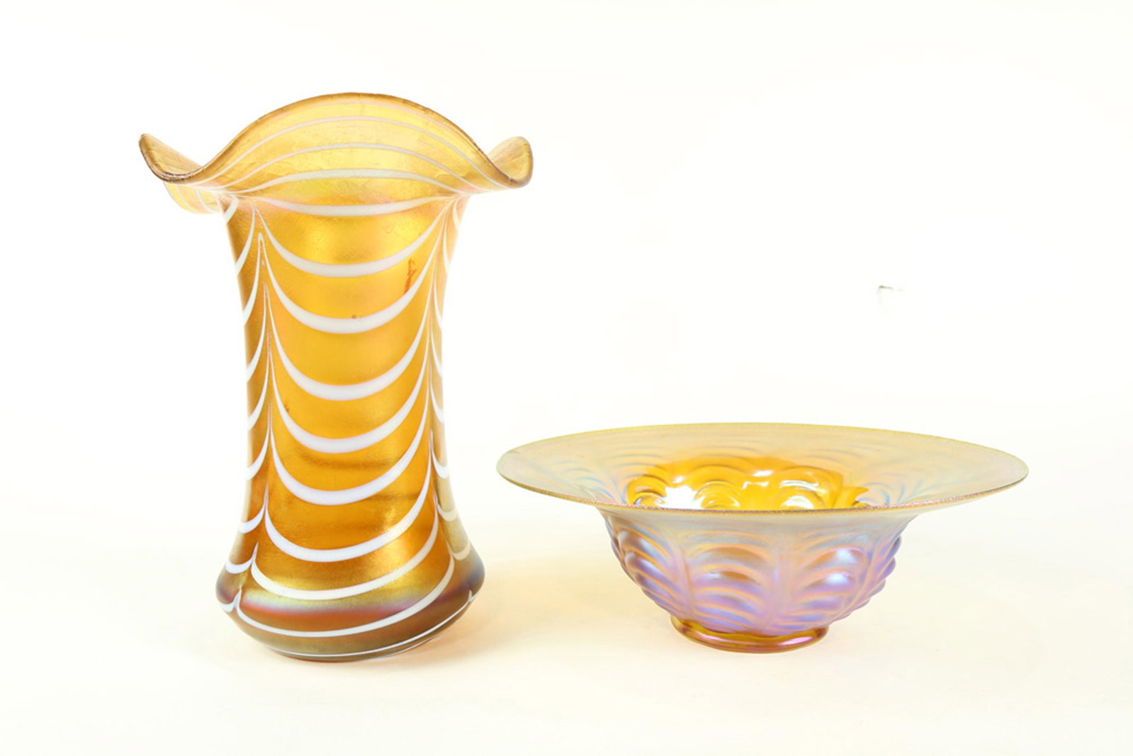 An iridescent art glass group early 20th century: An iridescent art glass group early 20th century, consisting of a shallow bowl having a pulled body 3"h x 8.5"w, together with a cylindrical vase, having a shaped rim above the pulled body 8.5"h each 