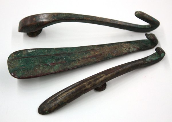 Chinese bronze belt hooks: (lot of 3) Chinese bronze belt hooks, one possibly Eastern Zhou dynasty (770-256 BCE), one garment fastener with a wide fluted curved shalf and simple hook terminal, the next sightly smaller and with 