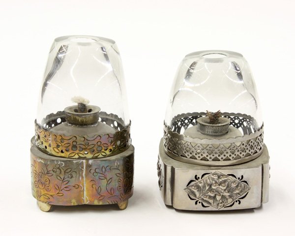 Chinese Small Lamps: (lot of 2) Chinese metal and glass opium lamps, each with a tapering glass funnel resting on a metal base, one inscised with flowers and scrolling sprigs and the other with repousse floral reserves, 4