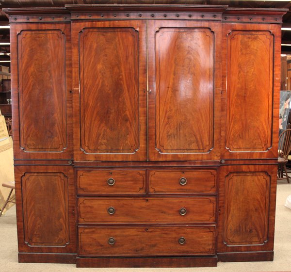 mahogany breakfront linen press: Early to mid-19th century crotch mahogany blind door breakfront linen press having molded cornice above bull's eye, centered with double doors over two short drawers above two long drawers, flanked by