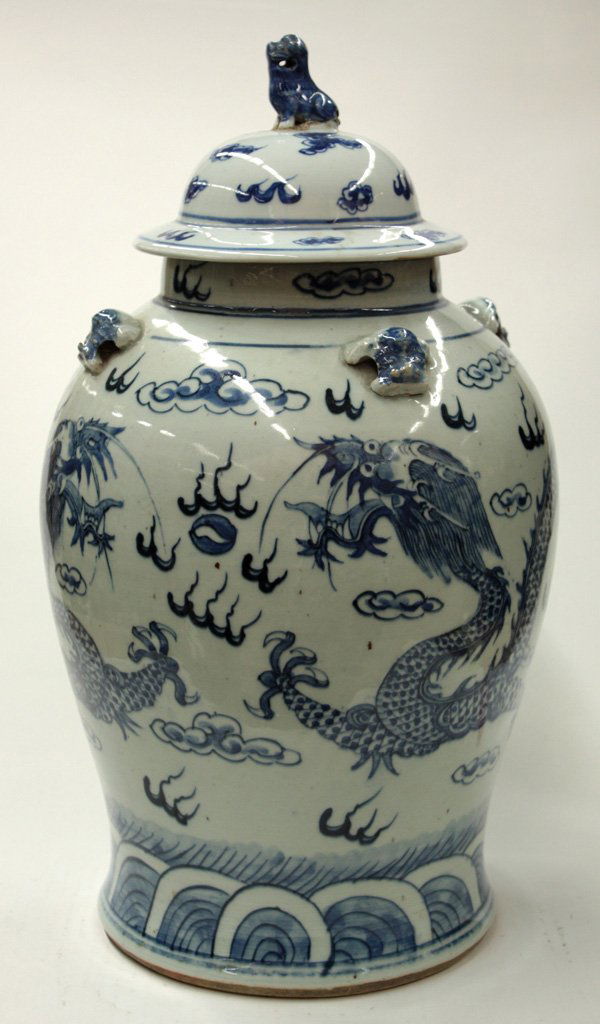 Chinese Blue and White Covered Dragon Jar: Chinese unglazeblue decorated ovoid jar and cover, painted in shades of cobalt blue with a pair of dragons contesting a flaming jewel amid cloud scrolls above stylized waves, four animal-mask handles