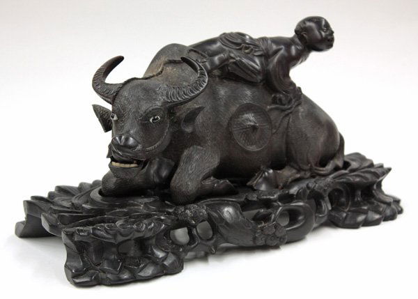 Chinese Hardwood Carving, Herd Boy and Ox: Chinese large ebonized hardwood figural group, well carved and delicately incised as a large recumbent water buffalo surmounted by a herd boy climbing over its back with his hat dangling down to the f