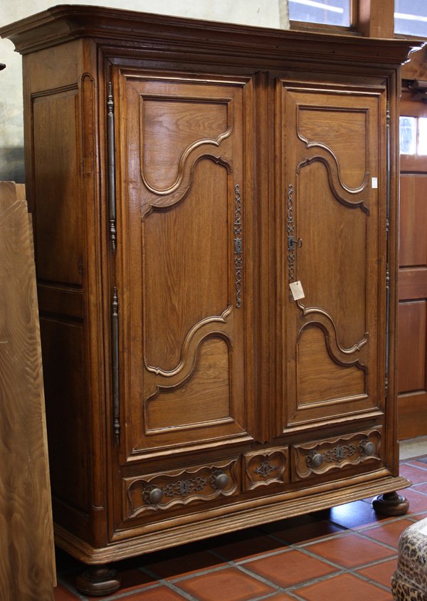 Louis XIV oak armoire: Louis XVI style oak armoire, fourth quarter 18th century, having shaped cornice, shaped and molded panel doors, the low drawers embellished with mounted and pierced hardware, resting on bun feet, 84''