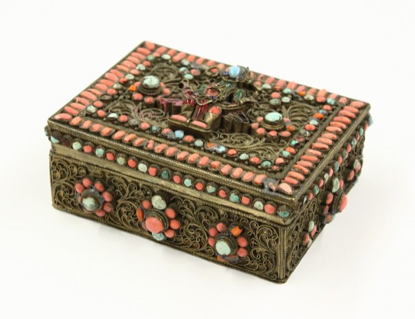 Nepalese Inlaid Box with Turquoise/Coral: Nepalese inlaid gilt metal box, the rectangular hinged lid with coral and turquoise inlays framing the deity to the center amid a filigree ground, the sides similarly decorated with flowers amid scrol