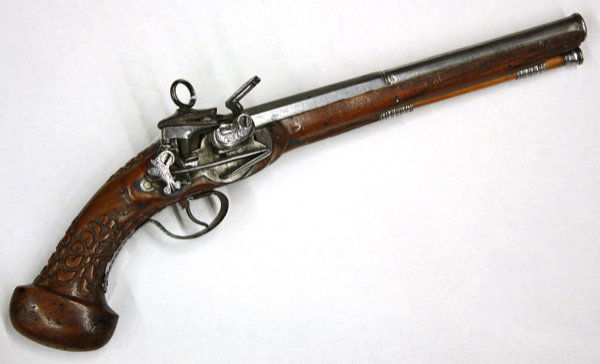 Flintlock pistol: Flintlock pistol, 11'' Barrel, 5/8'' bore, retains ramrod, relief carved walnut stock, engraved steel action, mounted carrying clip on left side