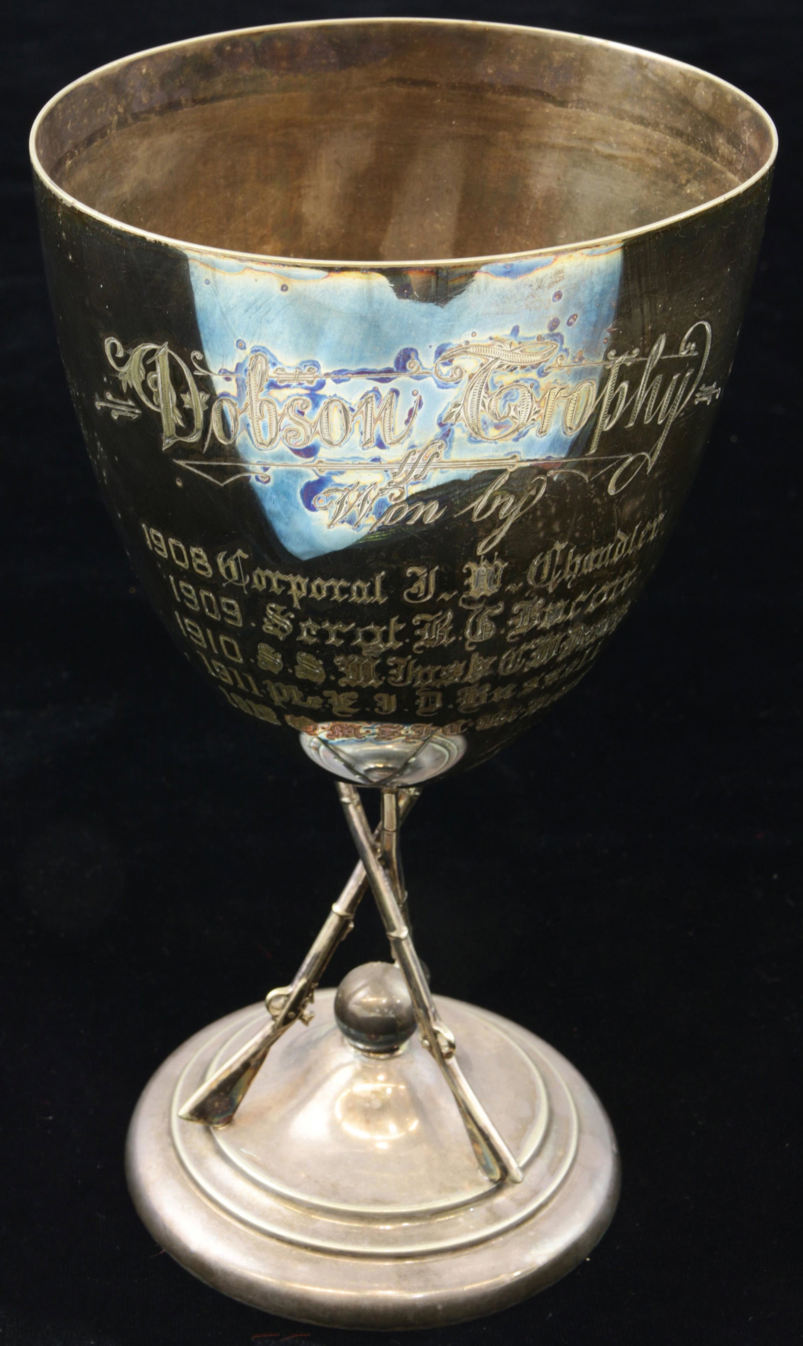 English Dobson Trophy plated chalice on rifle supports: English military "Dobson Trophy" plated chalice, with inscribed winners from 1908-1912, the large cup rising on rifle supports, 9.75"h x 5.25"dia.