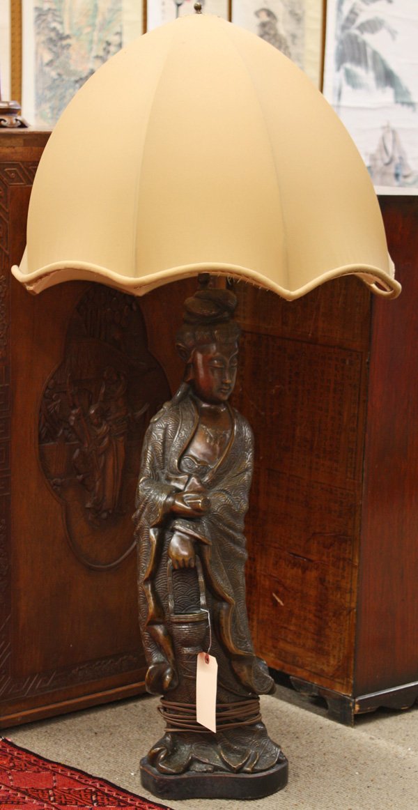 Chinese Large Bronze Guanyin, Electrified: Large patinated bronze statue of Guanyin, 20th century, fashioned as the base of a lamp, the Buddhist divinity standing in long brocade-patterned robes and holding a scroll and an open basket, all sup