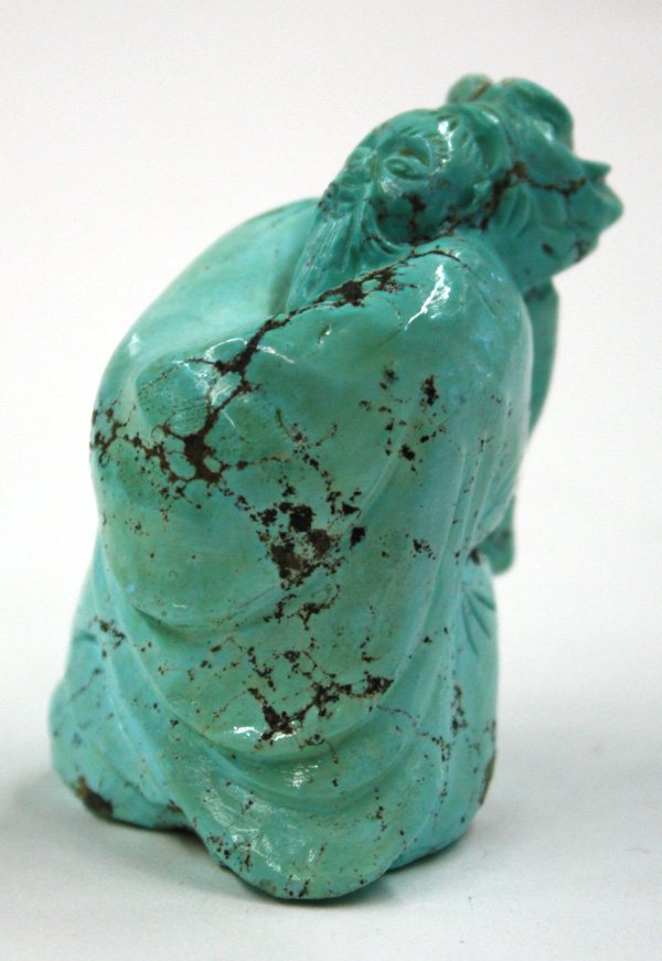 Turquoise Figurine of a Sage: Chinese turquoise figurine of a sage, carved with a serene beard face and a full body draped with loose robes falling in rhythmic folds, the matrix of mottled turquoise suffused with dark striations,