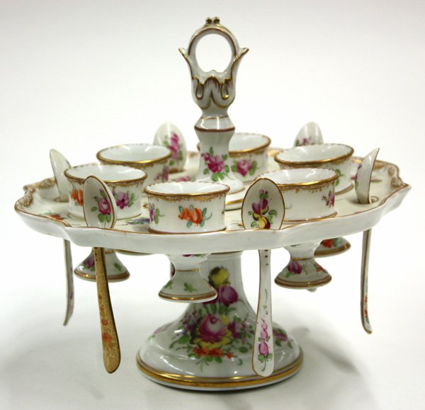 Continental porcelain egg server: Continental porcelain gilt and polychrome decorated egg serving set, having six cups with spoons all on a footed stand with a scalloped gilt edge, signed with crown and script D 8''h x 9''w, crack to 