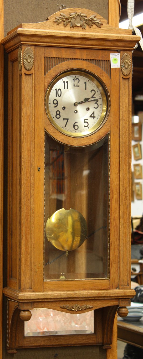 Edwardian oak wall clock: Edwardian oak wall clock with case having applied carvings and mirror back base, bevel glass door, and eight day time and strike spring driven movement,44''h x 16''w, case and movement key in office