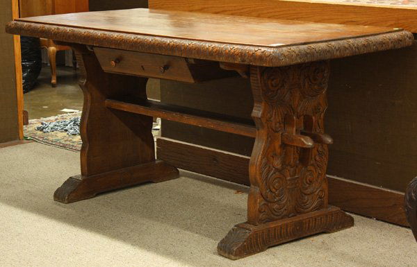 Fine carved arts and crafts era trestle table: Fine carved arts and crafts era trestle table, rectangular top with leaf carved molding, single drawer above carved sides rising on shoefoot base, 31''h x 64''w x 30''d