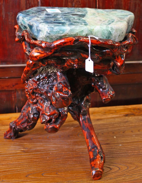 Hardstone/Wood Stool: Florite and phrase Hardstone and wooden stool/stand, with a gnarled wood base resting upon three supports and surmounted by a thick irregular slab of mottled green stone suffused with crystalline and 