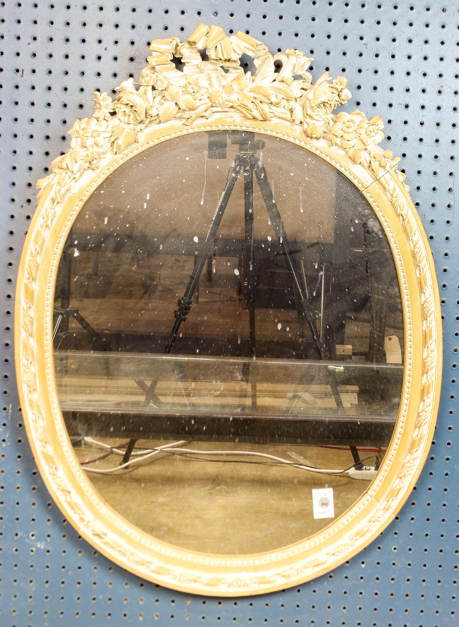 A French relief carved looking glass: A French relief carved looking glass, having a later white washed surface with a floral and bow decorated crest surrounding the oval mirror,